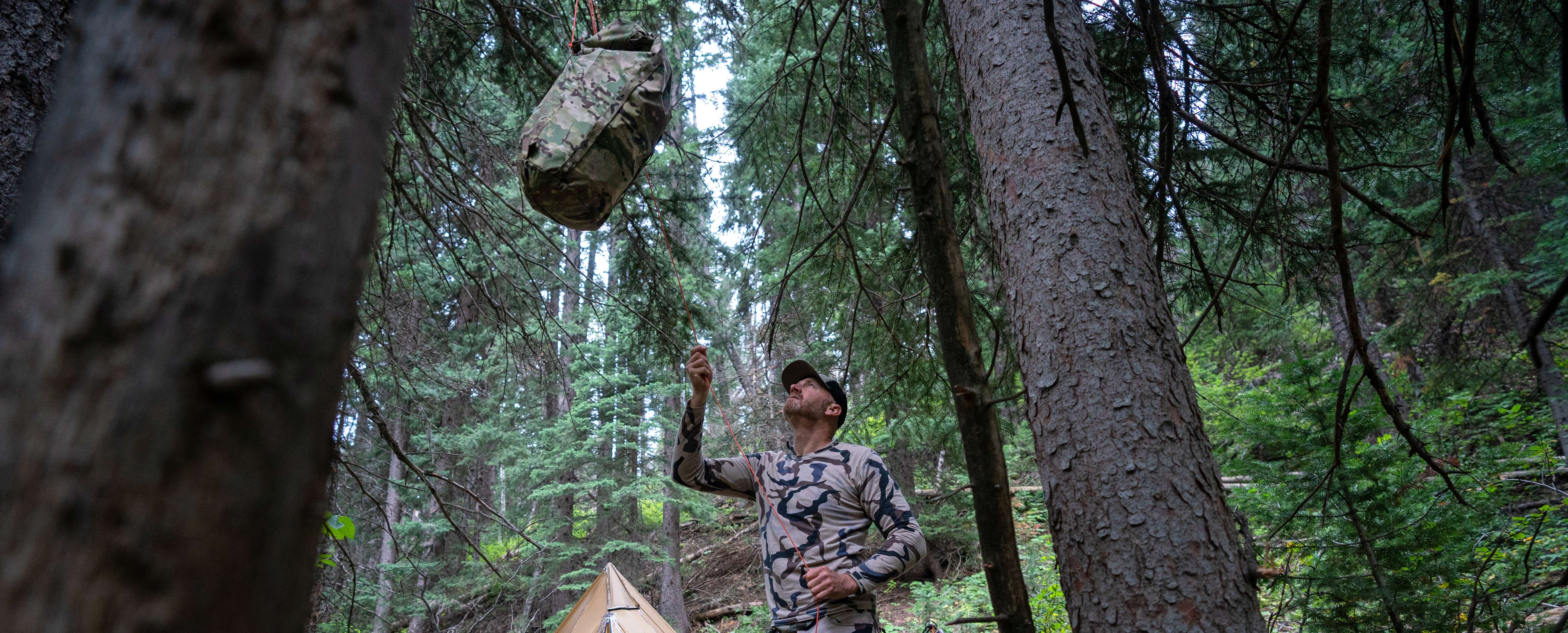 A man hanging his bag on a tree